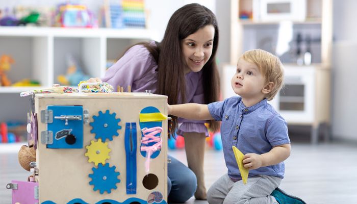 Infant and teacher playing with a busy board