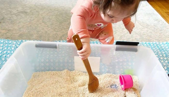 toddler playing with homemade rice sensory bin