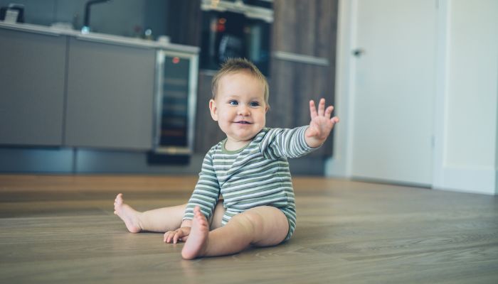 baby waving on kitchen floor